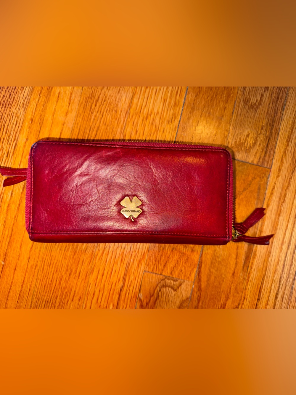 Red leather Lucky Brand zip-around wallet featuring a four-leaf clover logo